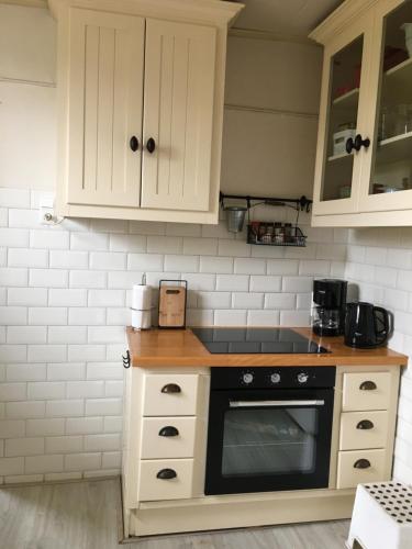 a kitchen with white cabinets and a black oven at Welkom op de Mildert in Nederweert