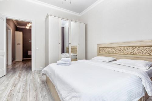 um quarto branco com uma cama grande e lençóis brancos em Raisson Ahotel D145 em Astana