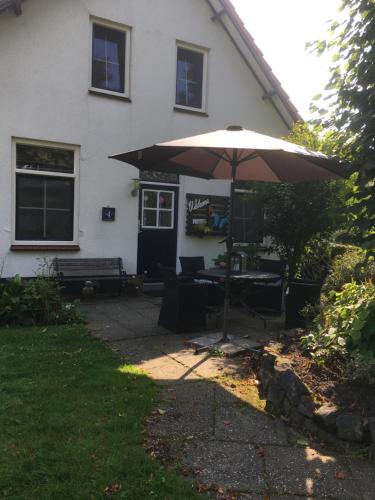 a patio with an umbrella in front of a house at Welkom op de Mildert in Nederweert