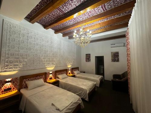 a hotel room with three beds and a chandelier at Dolon B&B in Bukhara
