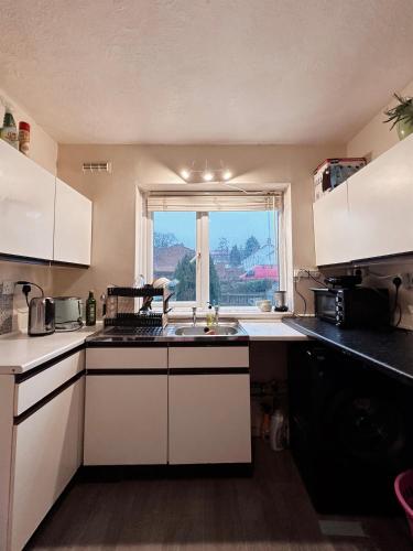cocina con fregadero y ventana en Come n Go - Homestay en Birmingham