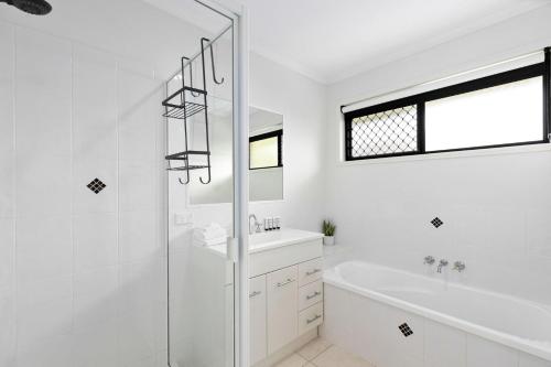 bagno bianco con doccia, vasca e lavandino di Relax at Moonstone a Urangan