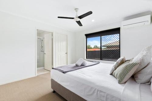 una camera bianca con un grande letto e un ventilatore a soffitto di Relax at Moonstone a Urangan