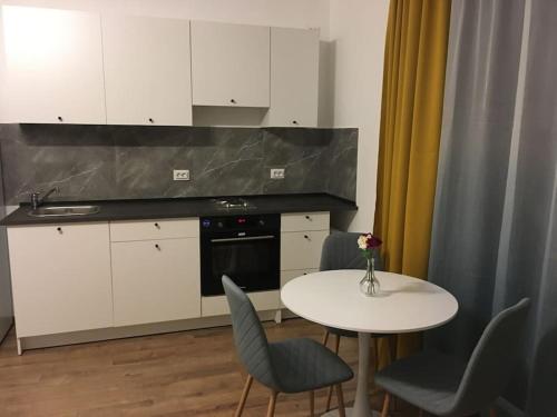 a kitchen with a white table and chairs and a table and a counter at Dbo-Vivo Mall Apartment in Baia Mare