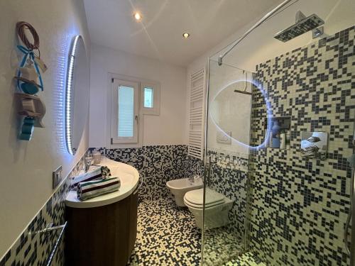 a bathroom with a toilet and a sink and a shower at Appartamento Viola Lignano Sabbiadoro con solarium in Lignano Sabbiadoro