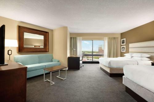 a hotel room with two beds and a couch at DoubleTree by Hilton Orlando Downtown in Orlando