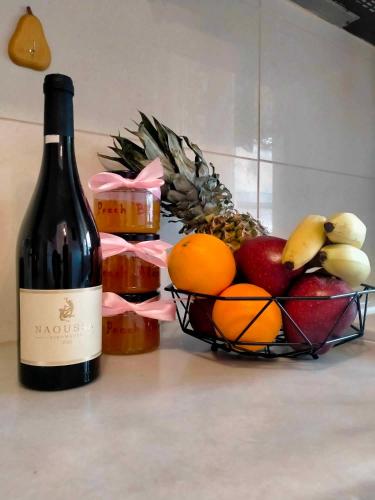 a bottle of wine next to a basket of fruit at 2BDR Downtown Veria Peach Blossom in Veria