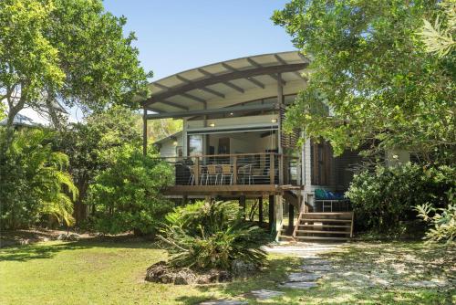a house with a porch and a deck at Fuller Holidays - Tuckeroo Beach House, Beachfront Suffolk Park in Suffolk Park
