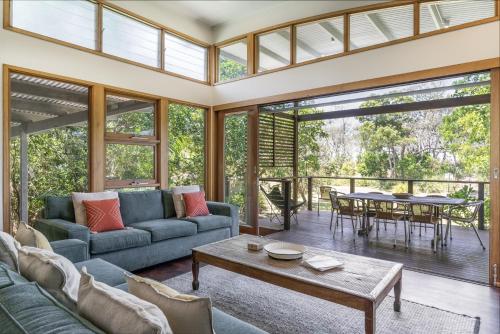 a living room with a couch and a table at Fuller Holidays - Tuckeroo Beach House, Beachfront Suffolk Park in Suffolk Park