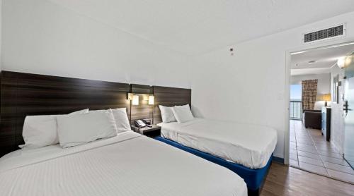 Habitación de hotel con 2 camas y balcón en SureStay Studio by Best Western Virginia Beach Oceanfront en Virginia Beach