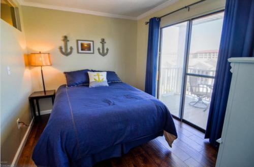 a bedroom with a blue bed and a balcony at Beach Place Seconds to Beach 6 in Panama City Beach