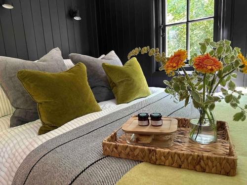 Una cama con una bandeja con un jarrón de flores. en Cornwall Woodland Dog Friendly Shepherd's Hut, en Bodmin