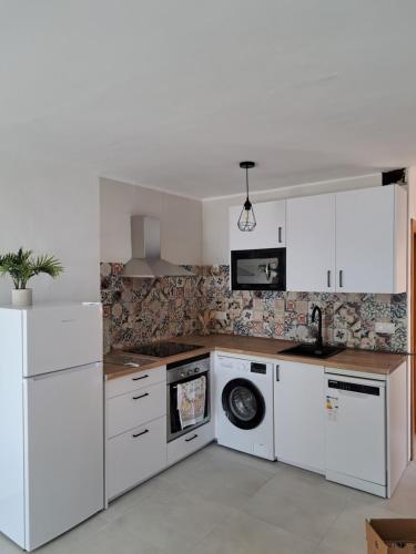 a kitchen with white cabinets and a washer and dryer at CASA PERSEA in Nerja