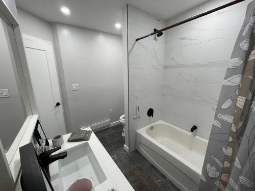 Brand New Modern unit in town! في Cochrane: حمام أبيض مع حوض استحمام ودش