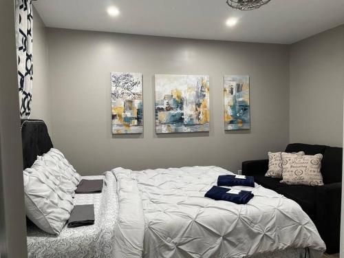 a bedroom with a bed and four paintings on the wall at Brand New Modern unit in town! in Cochrane