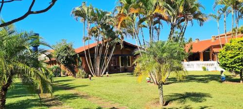 a house with palm trees in front of it at Chácara em Boituva com piscina e churrasqueira in Boituva