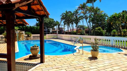 a swimming pool in a yard with a fence and trees at Chácara em Boituva com piscina e churrasqueira in Boituva