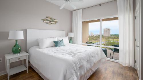 a white bedroom with a bed and a large window at Luau I 6708 in Destin