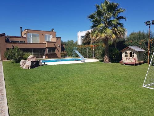 a yard with a pool and a palm tree and a house at Casa Las Palmas in Ciudad Lujan de Cuyo
