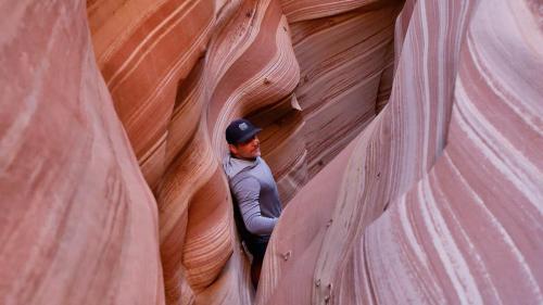 a man is walking through a slot canyon at Escalante Escapes Star Lily- Bunk Escape in Escalante