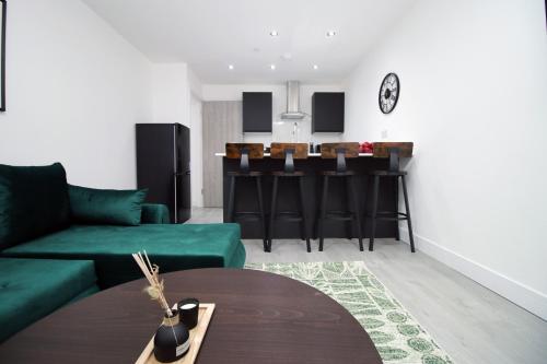 a living room with a green couch and a kitchen at New Cardiff Bloc Exclusive Apartments By Prime Stays - Shops and Parking - Great for Groups and Families in Cardiff
