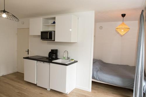 - une cuisine blanche avec un évier et un lit dans l'établissement Appart cozy rénové proche gares, balcon & parking, à La Madeleine