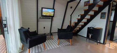 uma sala de estar com três cadeiras e uma televisão em Chale Brisa Do Mar em Palhoça