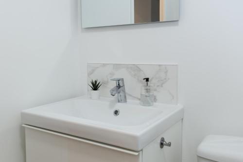 un lavabo blanc dans une salle de bain avec un miroir dans l'établissement Appart cozy rénové proche gares, balcon & parking, à La Madeleine