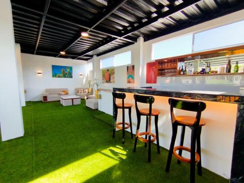 a bar with four stools in a room with green carpet at Suite Familiar en Puerto Ayora in Puerto Ayora