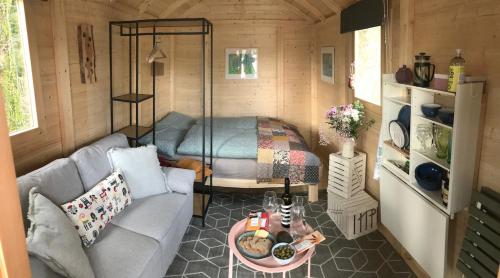 um pequeno quarto com um sofá e uma cama em Cosy Shepherds hut Between Maple and Hawthorn em Mountshannon
