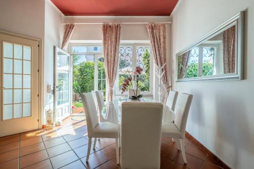 a dining room with a glass table and white chairs at Elegante Villa Lu' centro Città a 10 minuti dal mare in Cagliari