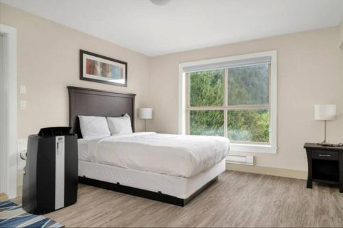 a white bedroom with a bed and a window at Harrison Lake Pets Welcome-3BR Penthouse Suite in Harrison Hot Springs