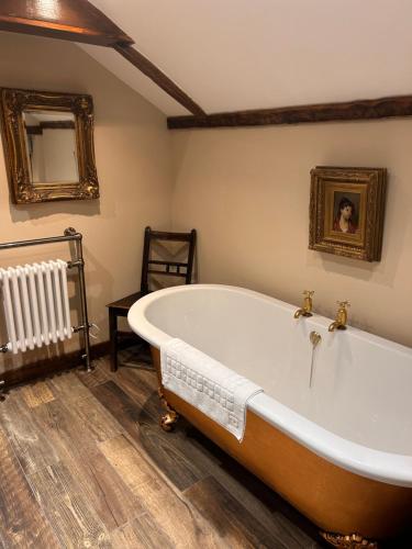 een groot bad in een badkamer met een spiegel bij NEW -Historic cottage with oak beams & period charm in Llangadog