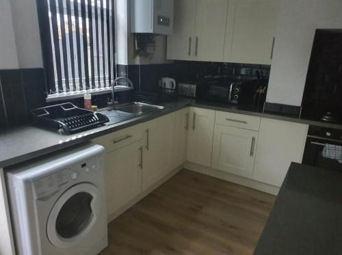 a kitchen with a sink and a washing machine at Home for all in Wincobank