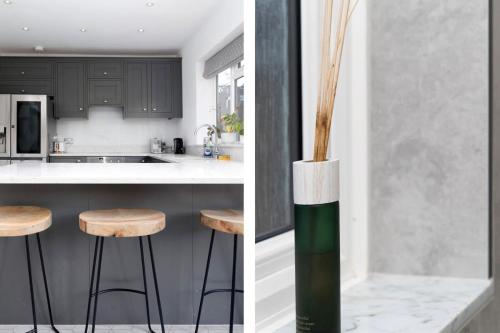 a kitchen with black cabinets and a counter with stools at Spacious London Haven for Family and Friends in London