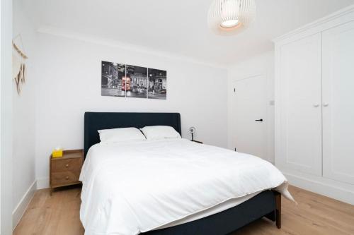 a white bedroom with a large bed with white sheets at Spacious London Haven for Family and Friends in London