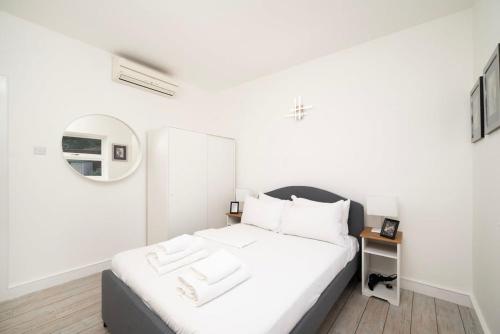 a white bedroom with a bed with white sheets at 2BR 2Baths ground floor garden apartment in Kingston upon Thames