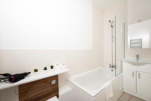 a white bathroom with a tub and a sink at 2BR 2Baths ground floor garden apartment in Kingston upon Thames