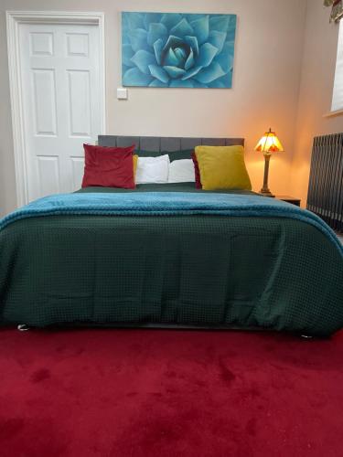 a bedroom with a large green bed with colorful pillows at Luxurious and Elegant Homestay in Kent in Wrotham