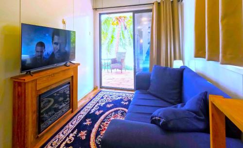 a living room with a blue couch and a flat screen tv at The Zanzibar Beach House-South in Pingwe