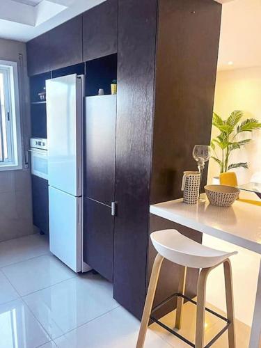 uma cozinha com um frigorífico branco e um banco em Le Privée 1 em Mindelo