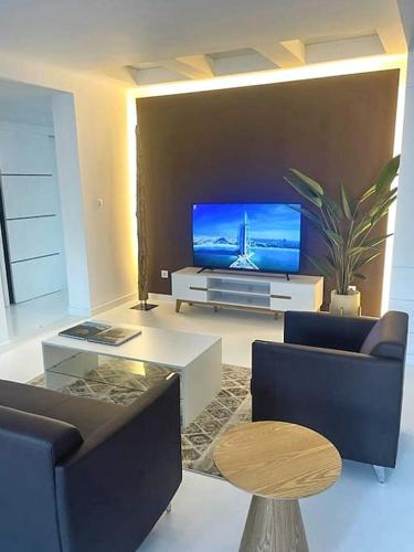 uma sala de estar com uma televisão de ecrã plano e cadeiras em Le Privée 1 em Mindelo