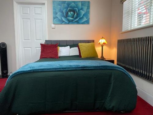 a bedroom with a green bed with colorful pillows at Luxurious and Elegant Homestay in Kent in Wrotham