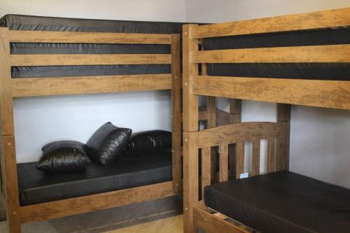 two brown bunk beds with black cushions on them at Chácara da Bia in Várzea Paulista