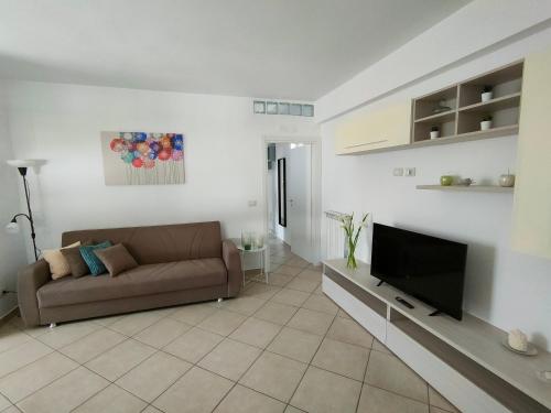 uma sala de estar com um sofá e uma televisão de ecrã plano em Serao House, 2 piano in centro em Mondragone