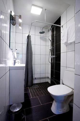 a white bathroom with a toilet and a sink at Adels Hotel in Oskarshamn