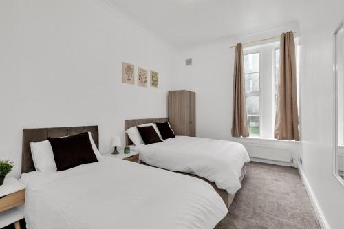 two beds in a room with white walls and a window at The Brixton Inn in London