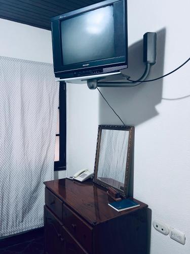 a television on top of a dresser with a mirror at Los Guacamayos La Ceiba in La Ceiba