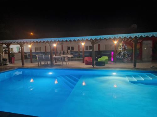 a swimming pool at night with a christmas tree in the background at Les Villas de Boisvin in Le Moule