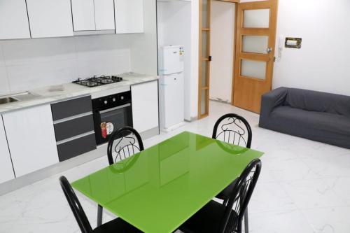 Figo Apartamentos في برايا: طاولة خضراء وكراسي في مطبخ مع أريكة